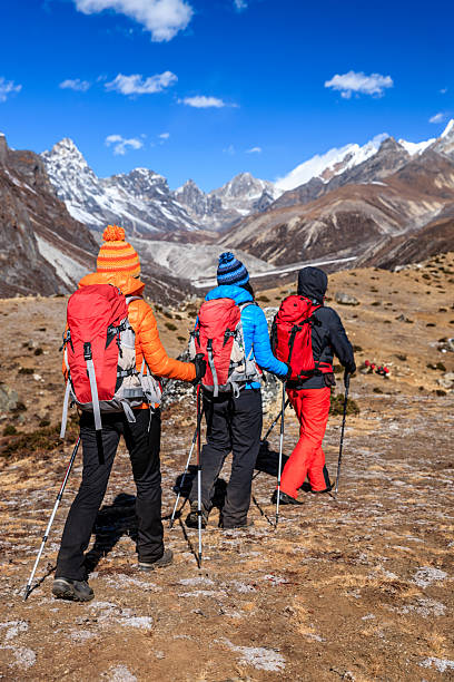 Sherpa porters carrying expedition equipment in traditional wicker baskets with headbands along the rocky moraine of the Imja Glacier towards the snowy slopes of Island Peak (6189m), the popular trekking peak deep in the Himalaya mountain wilderness of the Sagarmatha National Park, a UNESCO World Heritage Site, Nepal. ProPhoto RGB profile for maximum color fidelity and gamut.