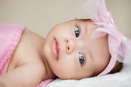 Newborn mixed race Hispanic caucasian baby girl with pink bow and blanket portrait