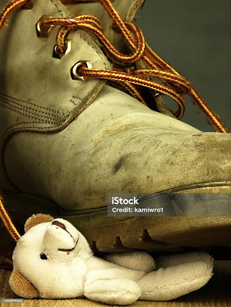 Teddy bear crushed by a heavy, old military boot. Children's toy, teddy bear under the old, dirty and heavy military boot. The view from the perspective of frogs. 2015 Stock Photo