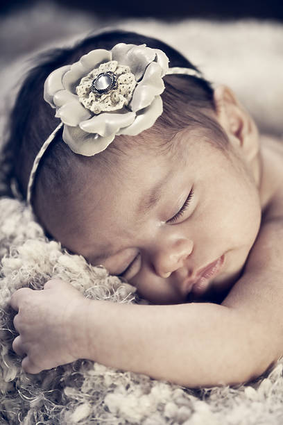 Portrait of a mixed race newborn baby girl asleep in blankets with vintage filtered effect