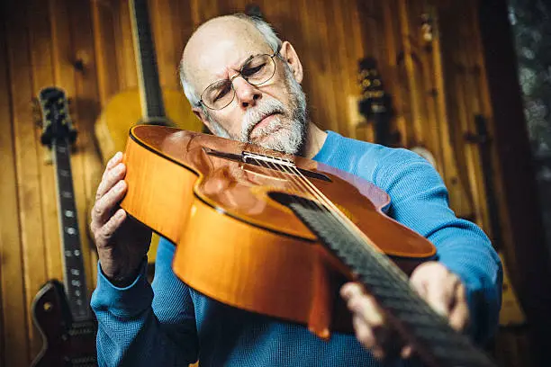 Instrument maker examining a classic guitar in workshop