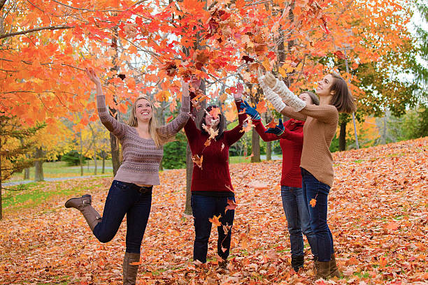 Four young women having fun together in a colorful park in fall