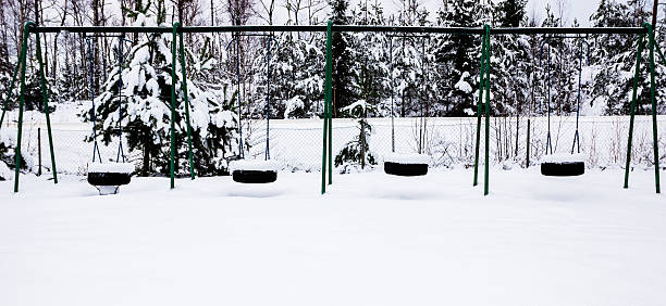 A four swingset at snowy playgrond/park