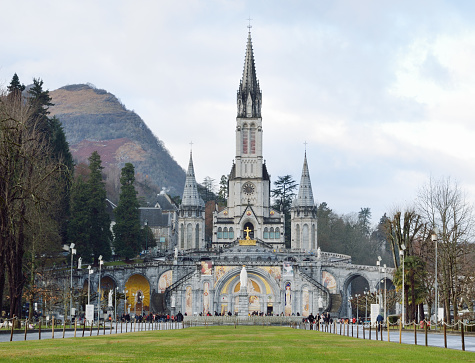The Basilica of our Lady of the Rosary is a Roman Catholic church and minor basilica in Lourdes. Tourists and believers are in front of the Rosary basilica.