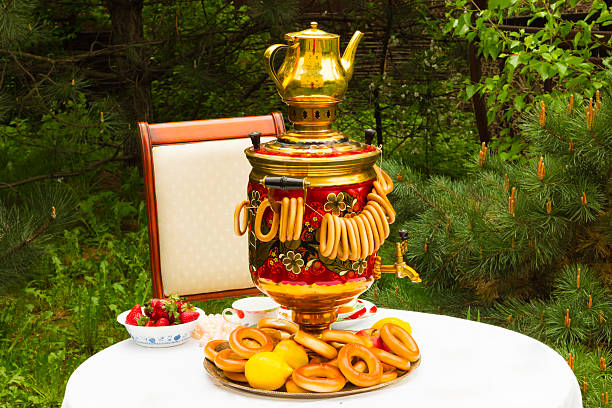 Spring tea party in the garden, on a table covered with a white tablecloth, Russian samovar and tea, strawberries on the plate Gzhel, lemons, flowers, drying and bagels, Russian national colors, pearl and quartz beads adorn the composition.