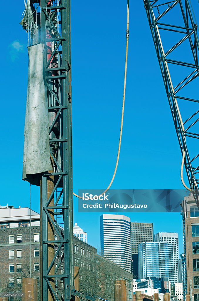 Pile driver driving poles for foundations of new building Pile driver driving steel poles for foundations of new building south of downtown Seattle WA 2015 Stock Photo