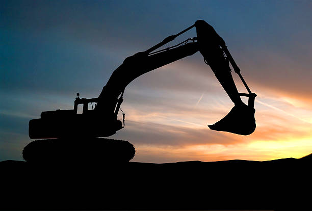 istock silhouette of Excavator loader at construction site with raised 535966283