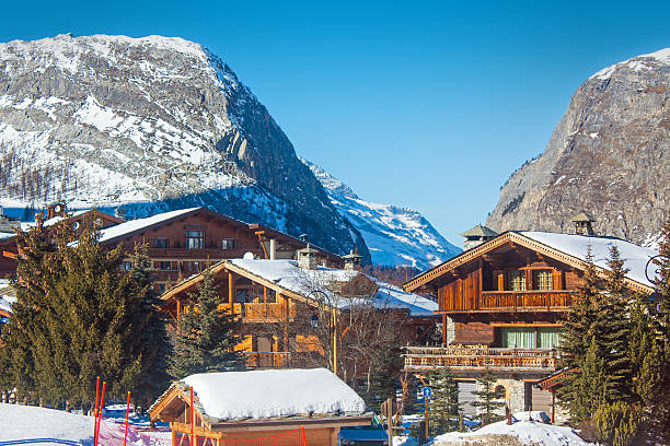 With scattered mountain cabins, snowy forest slopes, and soft alpine mist covering the landscape