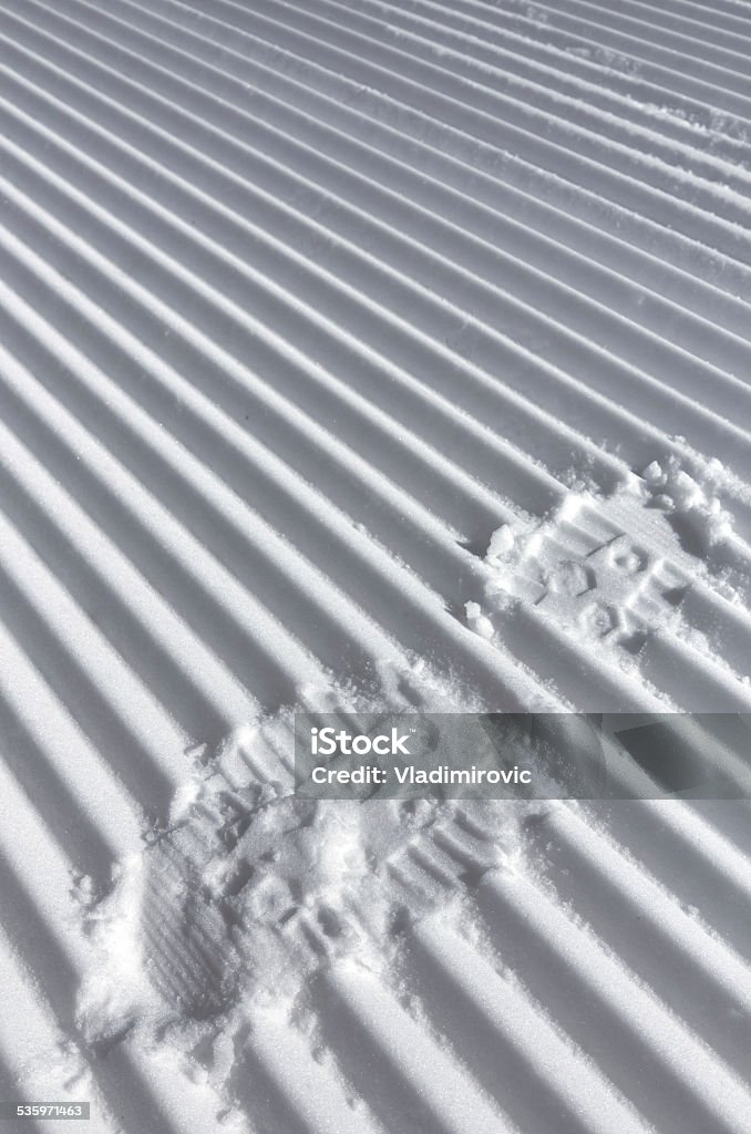 Foot track on the fresh striped prepared slope Foot trace on the fresh striped prepared slope, strips lines of snowcat, close up 2015 Stock Photo