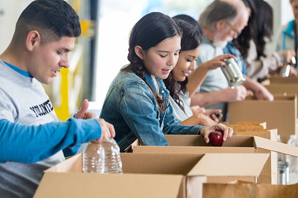 diverso grupo de voluntários ordenar os donativos em caixas de - food donation box groceries canned food imagens e fotografias de stock