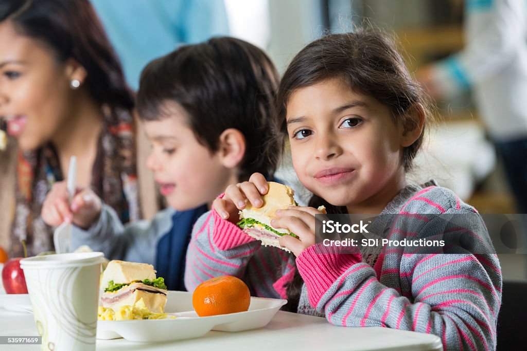 Young Hispanic family eating meal at neighborhood soup kitchen Child Stock Photo