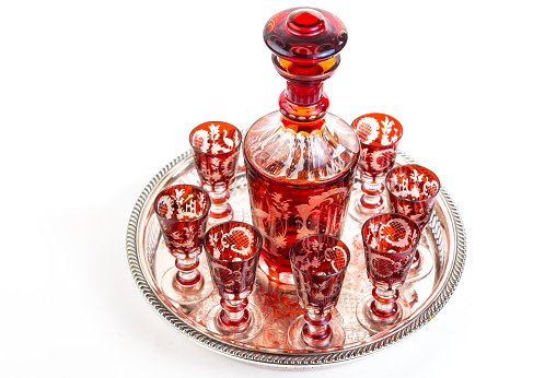 Overhead view of Set of red Bohemiam Cordial Glasses and Decanter in Silver Serving Tray.  Horizontal on white background with copy space.