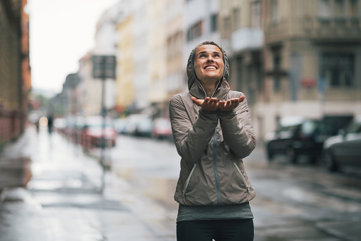 happy fitness young woman catching rain drops in the city