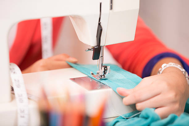 seamstress sews tela, ropa con máquina de coser. primer plano. - craft adult blue busy fotografías e imágenes de stock