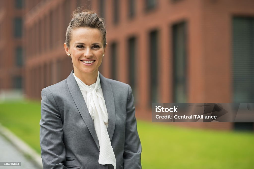 Smiling business woman in front of office building Portrait of smiling business woman in front of office building Adult Stock Photo