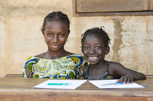 Couple of beautiful African children sitting in their desk at school in Bamako, Mali. They are enjoying school time. Blurred background.