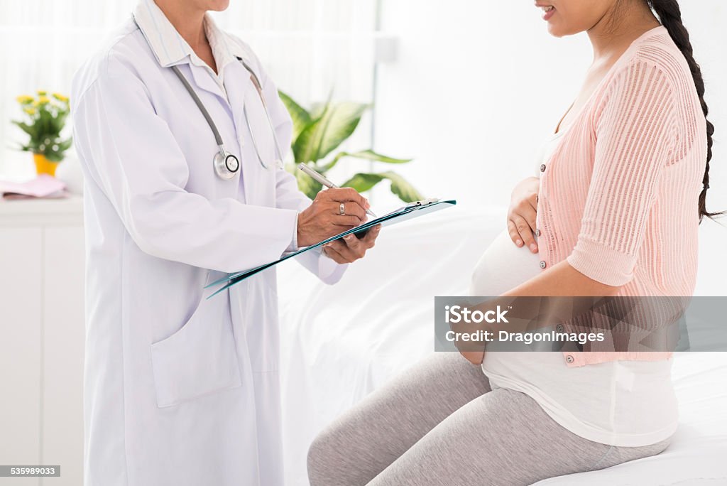 Examination Cropped image of pregnant woman visiting doctor 2015 Stock Photo