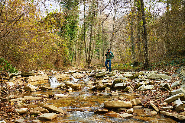 istock Hiker young man crossing a river on stones 536008615