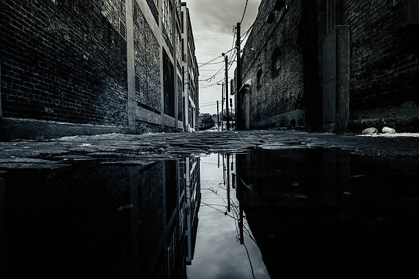 Dark Backstreet and Reflection on a Puddle Dark backstreet in usa ghost town stock pictures, royalty-free photos & images