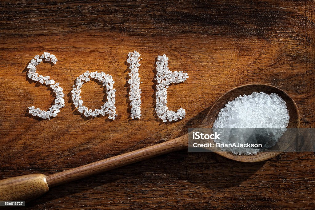 Sea salt Sea salt on wooden spoon and the word salt written in grain Salt - Seasoning Stock Photo