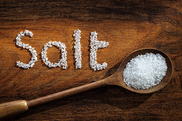 Sea salt Sea salt on wooden spoon and the word salt written in grain sodium stock pictures, royalty-free photos & images