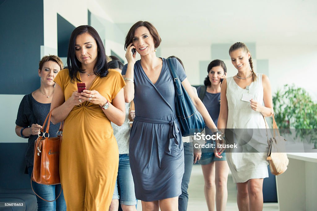 Group of women walking the hall Group of women walking down the hall, texting or talking on mobile phone. Office Stock Photo