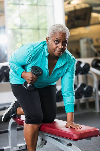 senior african american woman ジムでのウェイトリフティング - gym women inside of exercising ストックフォトと画像
