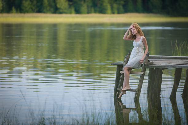 Beautiful woman resting on the bridge on the lake.