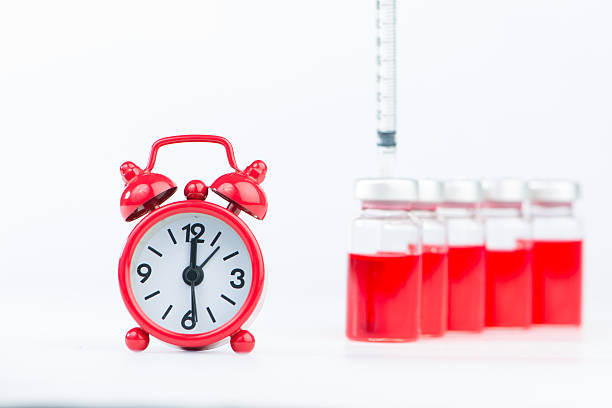 istock Red alarm clock and injection vials background 536035393