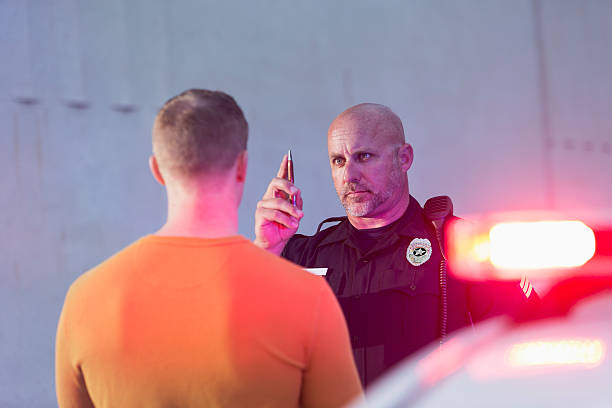 Policeman performing sobriety test on driver Police officer giving sobriety test to young man to see if he is driving under the influence of drugs or alcohol.  Police cruiser is out of focus in the foreground. driving under the influence stock pictures, royalty-free photos & images