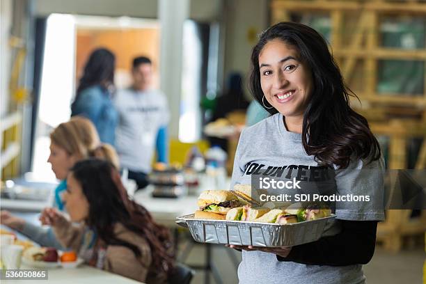 Friendly Hispanic Woman Serving Food At Neighborhood Charity Soup Kitchen Stock Photo - Download Image Now