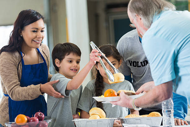 Young Hispanic family volunteering to serve food in soup kitchen Young Hispanic family volunteering to serve food in soup kitchen soup kitchen stock pictures, royalty-free photos & images