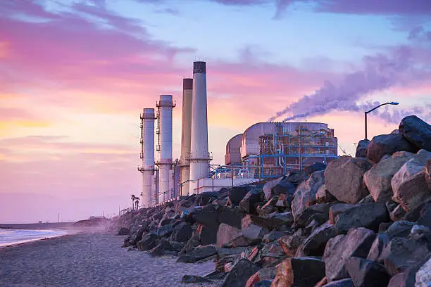 A power plant sits on the beach and runs and uses energy at twilight.