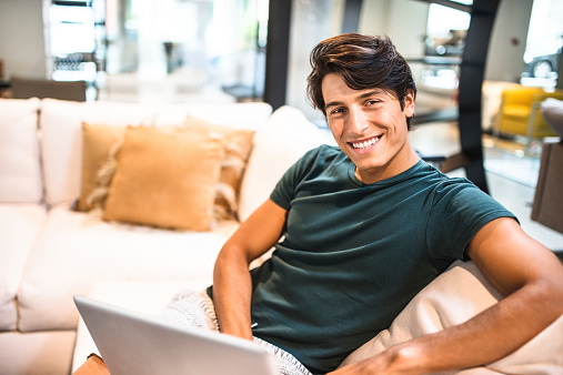 Cheerful man relaxing online on sofa
