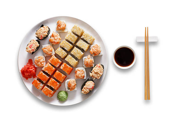 Set of sushi maki and rolls isolated at white. Japanese food restaurant, sushi maki gunkan roll plate or platter set. Chopsticks, ginger, wasabi and soy sauce. Sushi at white round plate isolated at white background. japanese cuisine food rolled up japanese culture stock pictures, royalty-free photos & images