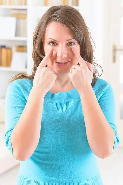 Woman doing EFT on the under eye point. Emotional Freedom Techniques, tapping, a form of counseling intervention that draws on various theories of alternative medicine.