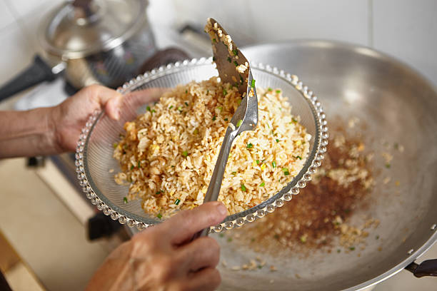 Finish cooking Finish cooking the friend rice and lift it up on a plate, focus on the spatula might have some blur movement chinese cuisine fried rice asian cuisine wok stock pictures, royalty-free photos & images