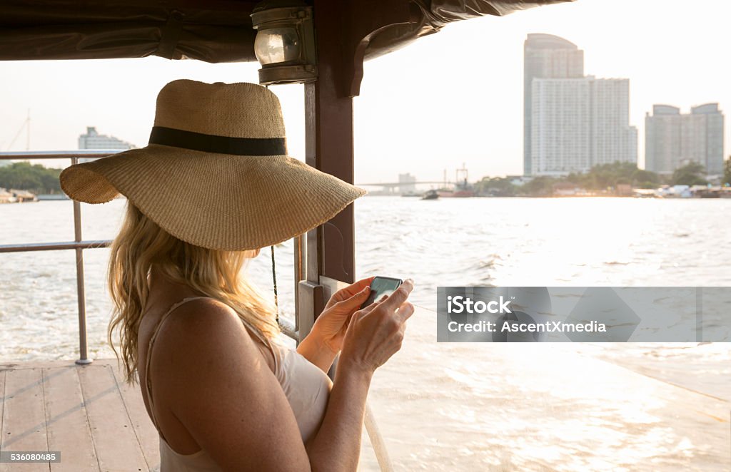 Woman takes pic with smart phone, on river boat Woman takes pic with smart phone, on river boat, Bangkok 2015 Stock Photo