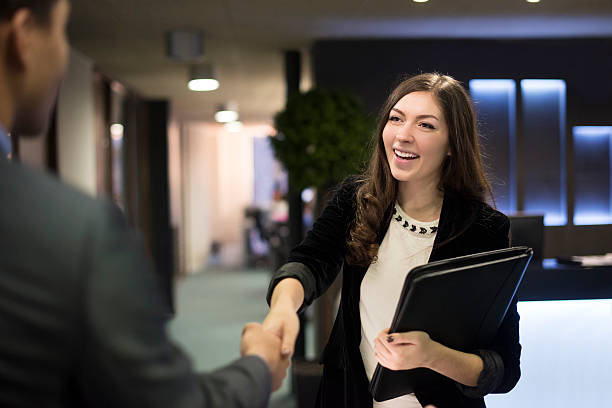 young woman shakes hands with her potential new boss young woman arrives at her interview , resume under her arm greeting her interviewer good cv stock pictures, royalty-free photos & images