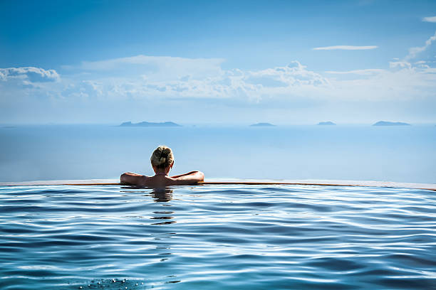 mujer relajarse en la piscina de borde infinito de vacaciones - balneario fotografías e imágenes de stock