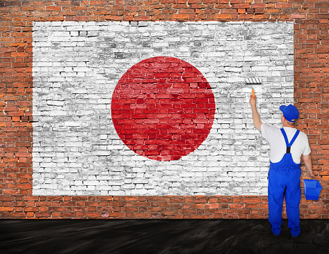 House painter paints flag of Japan on old brick wall