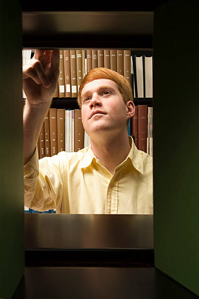 istock Male student choosing a book in the library 536094529