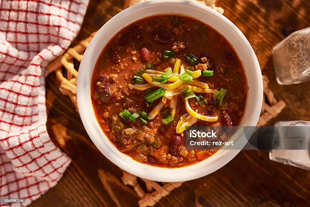 bowl of chili overhead photo of a bowl of chili with cheese and green onions Chili Con Carne Stock Photo