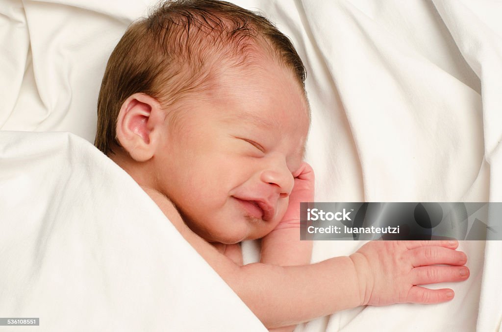 New born baby boy smiling in his sleep. Ten days baby happy laughing during his nap. 0-1 Months Stock Photo