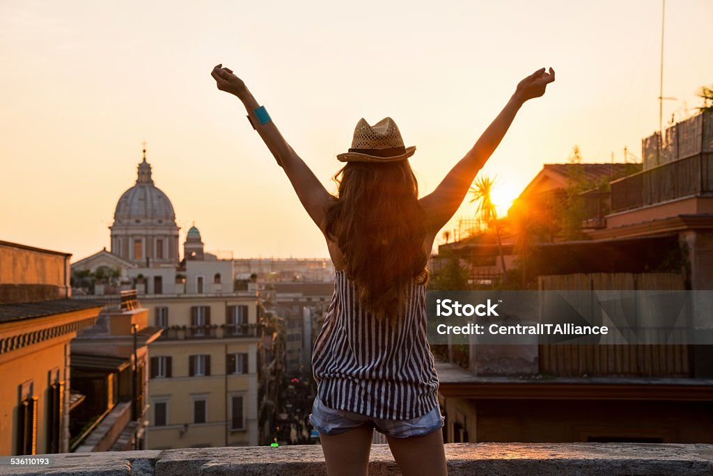 Young woman looking on rooftops of rome Young woman looking on rooftops of rome on sunset and rejoicing. rear view 2015 Stock Photo