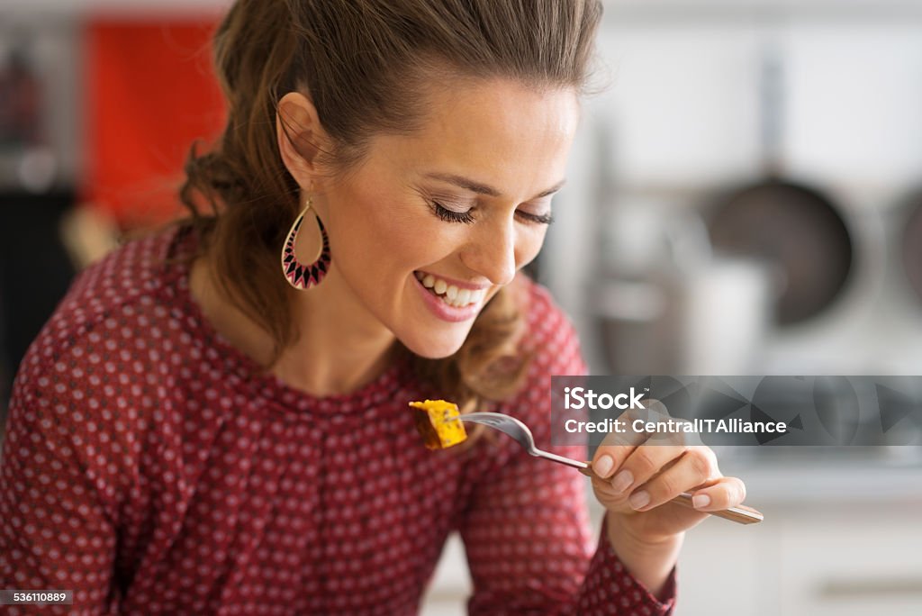 portrait of happy young woman eating in kitchen Portrait of happy young woman eating in kitchen 2015 Stock Photo