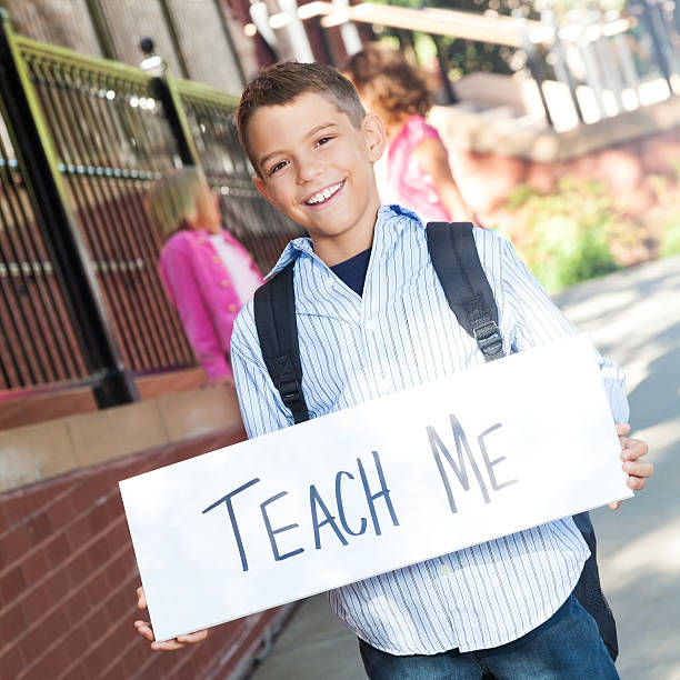 istock Elementary boy holding 'teach me' sign at school 536111968