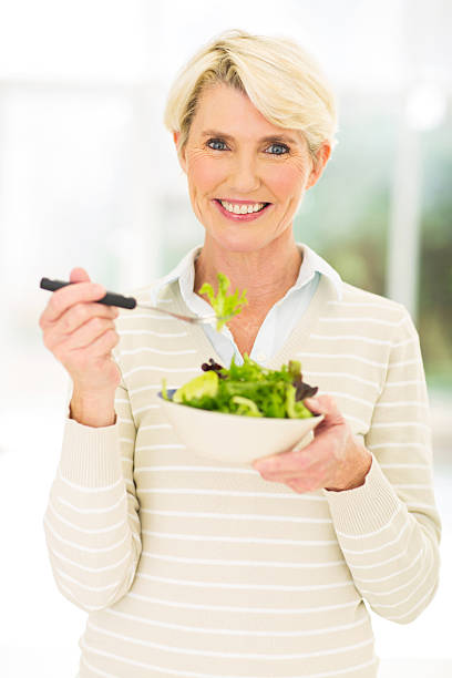 istock middle aged woman eating salad 536141311