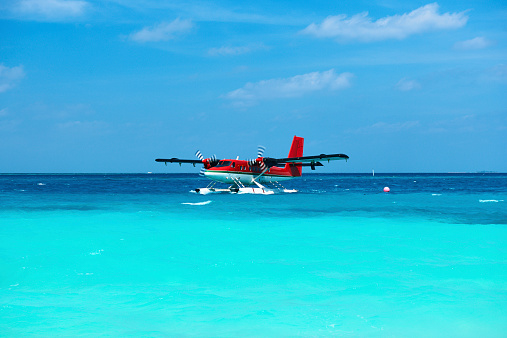 A fixed-wing propeller airplane is about to land at a primitive airport on a tropical island. Surrounding the airport are lush tropical vegetation, with the azure ocean and pristine beaches in the distance. The arrival of this small aircraft heralds the beginning of a relaxed and leisurely vacation journey. Captured with the Leica Q3.
