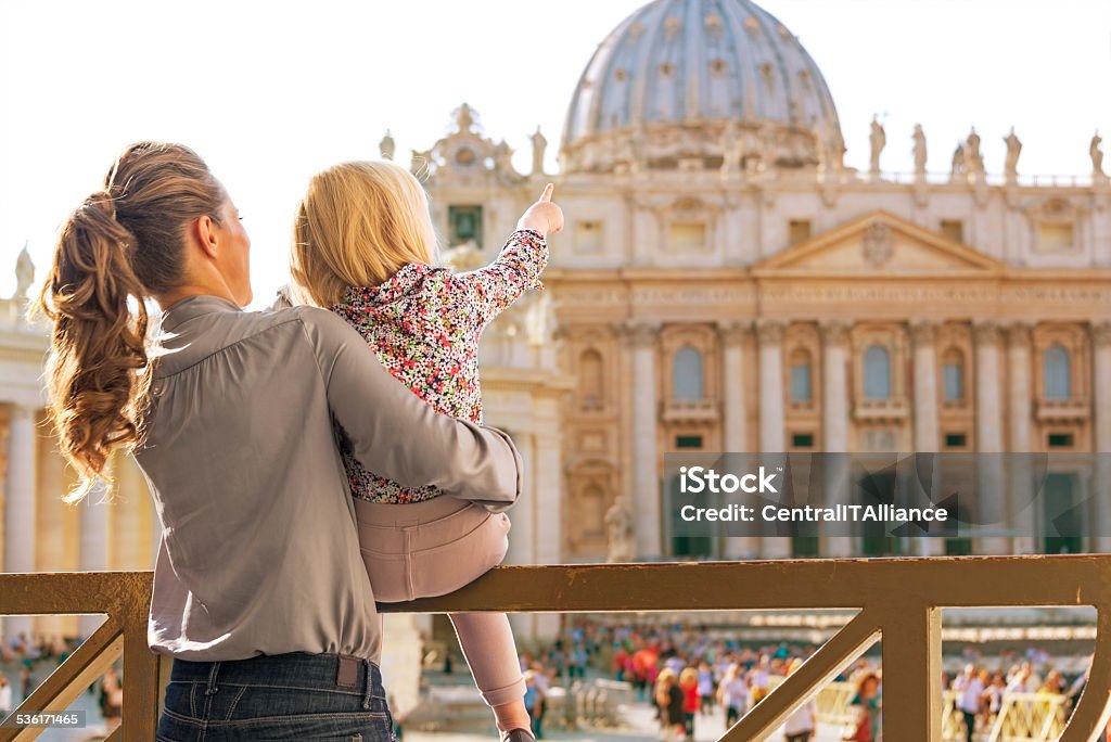 Mother and baby girl pointing on basilica di san pietro Mother and baby girl pointing on basilica di san pietro in vatican city state. rear view Family Stock Photo